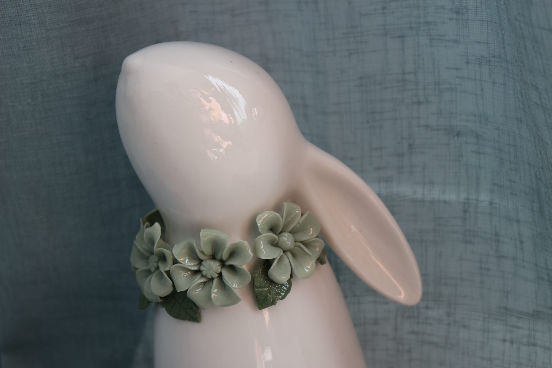 Lapin en porcelaine blanche avec un très joli collier de fleurs vertes en porcelaine, une décoration douce pour l'univers de bébé.